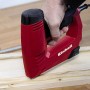 Einhell Elektrotacker TC-EN 20 E in Nutzung auf Holz, rot/schwarz. Inkl. Klammern und Nägel.