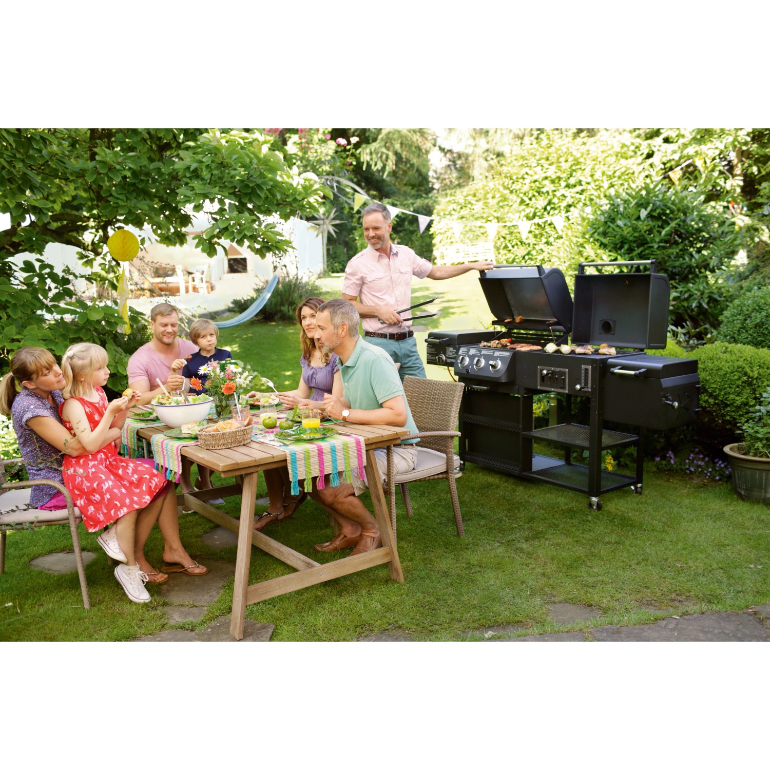 Familie grillt mit dem Jamestown Kombigrill Drake im Garten. Holzkohlegrill mit Gasgrill und Smoker.