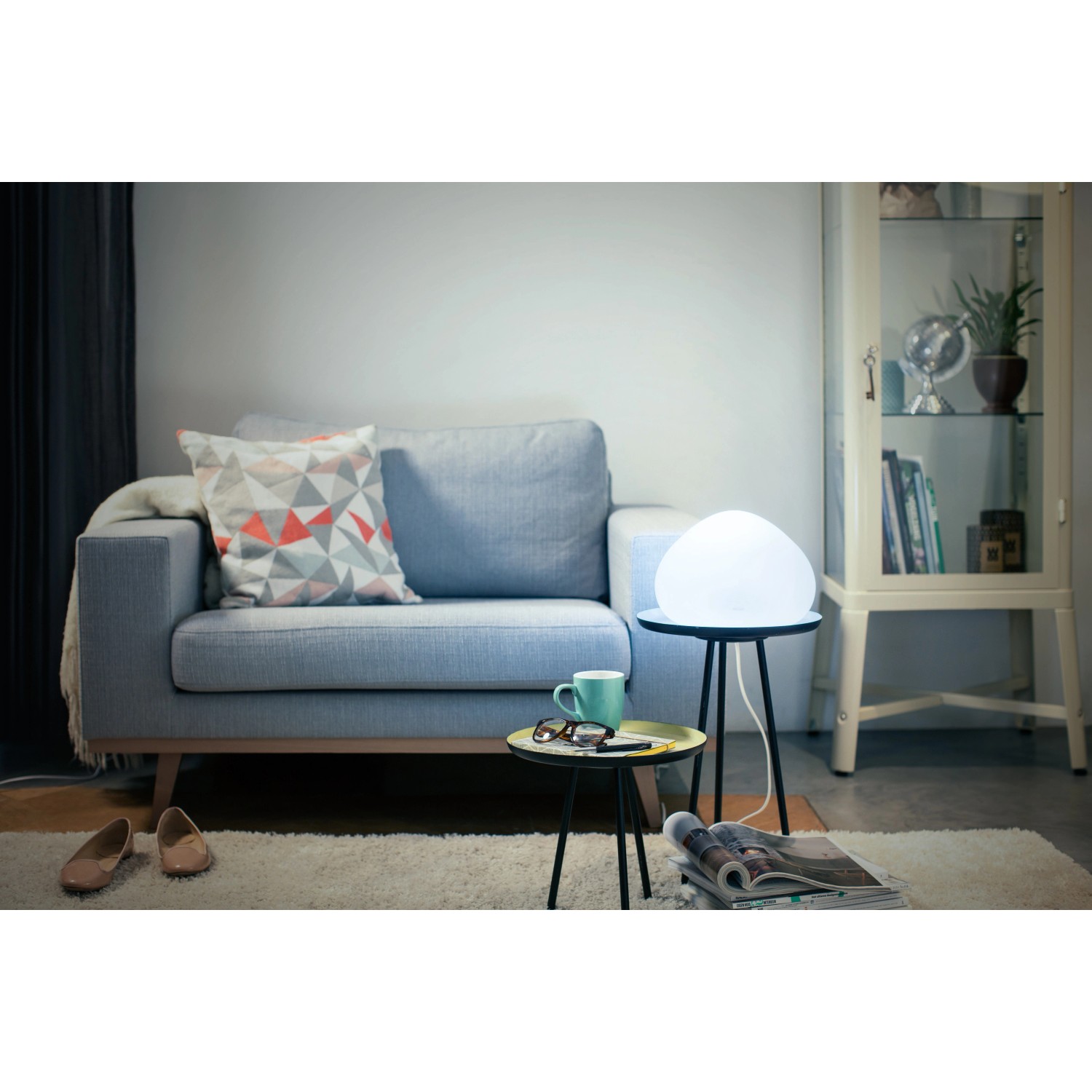 Weiße Philips Hue Wellner Tischleuchte mit Dimmer auf kleinem Tisch im Wohnzimmer.