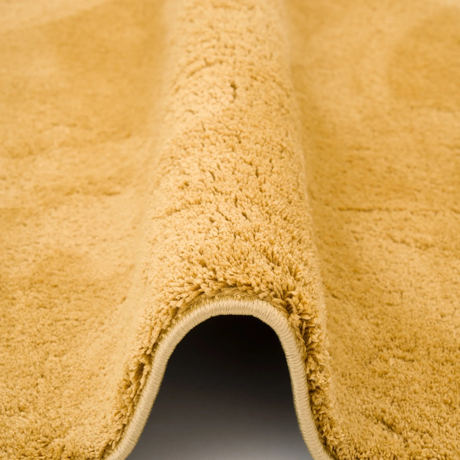 Detailansicht: Curryfarbener, runder Hochflor Teppich (200x200cm) mit weicher Textur.