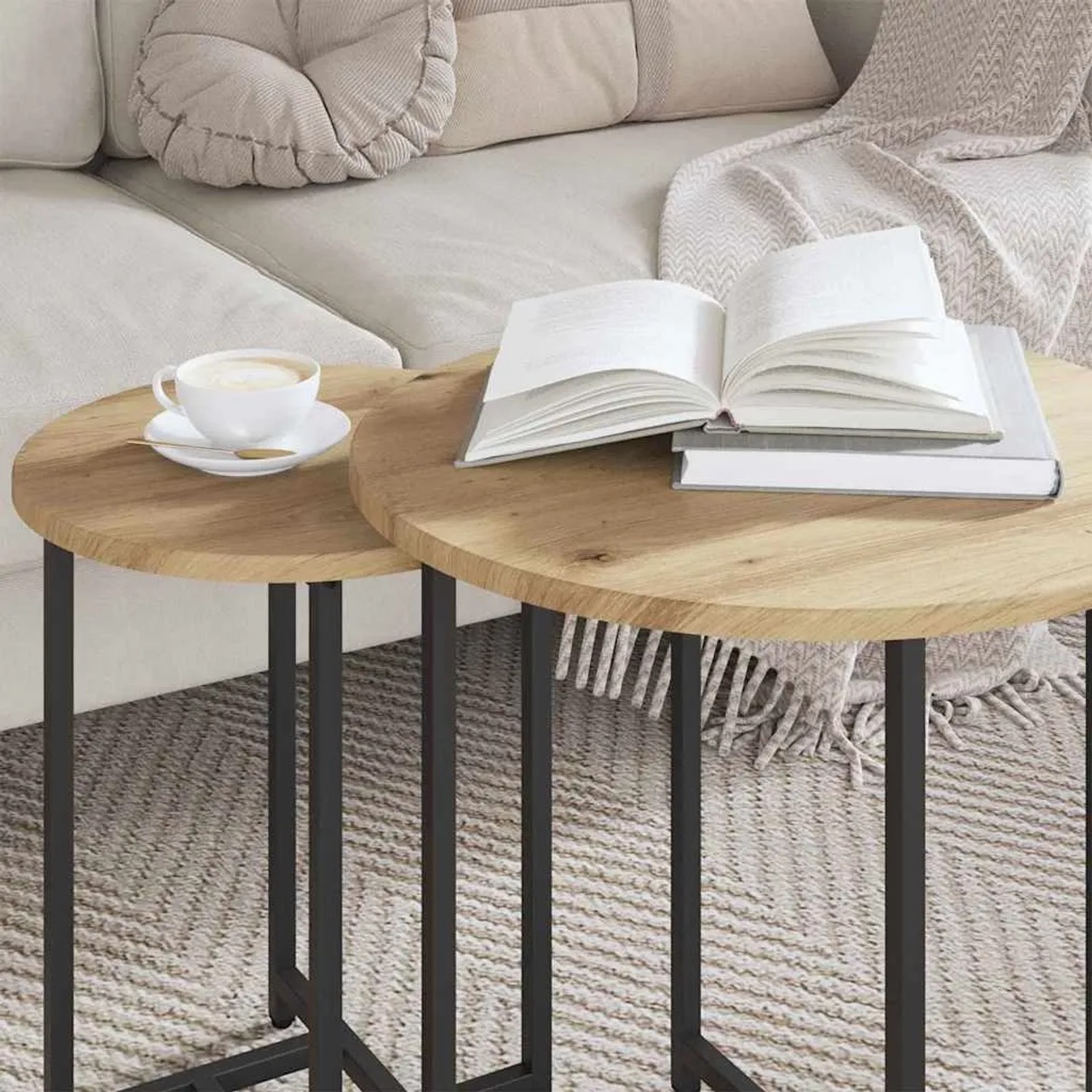 Rundes Beistelltisch-Set in Artisan Eiche und Schwarz, ineinandergeschoben, mit Tasse und Büchern am Sofa.