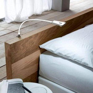 Weiße flexible LED Leseleuchte LUMINOSO am Holzbettkopfteil. Perfekt als Bett- oder Unterbauleuchte.
