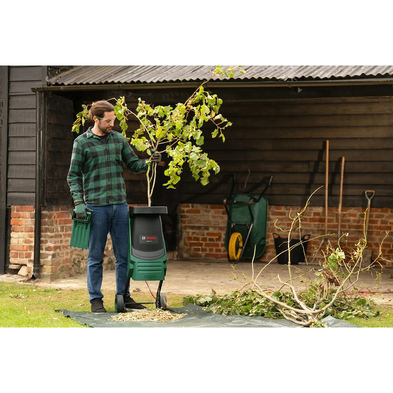 Bosch AXT Rapid 2200 Messerhäcksler im Einsatz mit Mann und Grünabfällen.