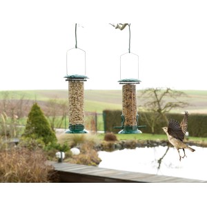 Zwei grüne Vogel-Futterspender "Feedy" Set mit Futter und Vogel im Flug im Garten.