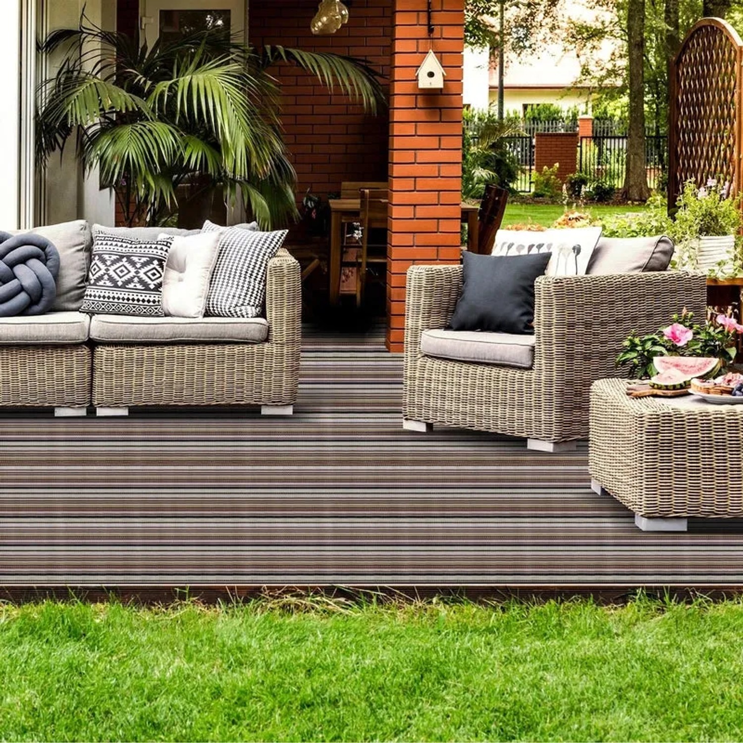 Gestreifter Outdoor Teppich Asti (180x300 cm) auf einer Terrasse mit Gartenmöbeln.