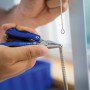 Hände nutzen blaues LUX 12-in-1 Mini-Multitool mit Zange an einer Feder.
