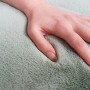 Nahaufnahme: Hand testet flauschigen, mintfarbenen Schöner Wohnen Badteppich Bali (67x110 cm).
