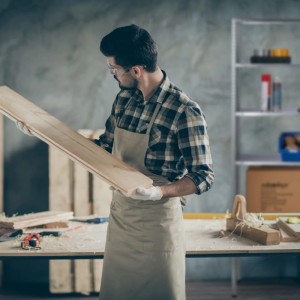 Mann mit Holz vor silbernem Relaxdays Schwerlastregal im Werkraum.