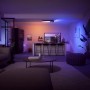 Schwarze Philips Hue Centris LED-Deckenleuchte mit 3 Spots in Wohnraum-Szene mit farbiger Beleuchtung.