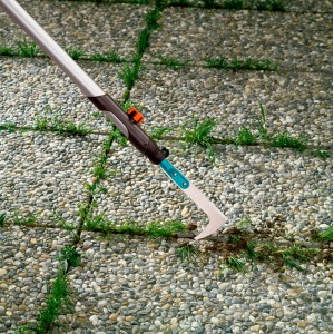 Gardena Fugenkratzer mit Holzstiel im Einsatz zum Entfernen von Unkraut zwischen Pflastersteinen.