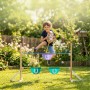 Kind springt mit Steckenpferd über höhenverstellbares Hobby Horse Hindernis aus Holz im Garten. Violett, Türkis.