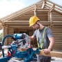 Mann sägt Holz mit Bosch Professional Kapp- und Gehrungssäge GCM 340-305 D vor Holzhaus. Präzises Werkzeug.