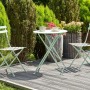 Mintgrünes Beliani Bistro Set FIORI: runder Metalltisch, zwei klappbare Gartenstühle auf Holzterrasse.