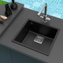 Schwarze Miló Einbauspüle Qubo 44 aus Granitverbundstoff mit Armatur auf dunkler Arbeitsplatte.