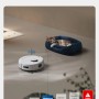 ECOVACS DEEBOT Mini Saugroboter bei der Arbeit, während eine Katze in einem Bett liegt.