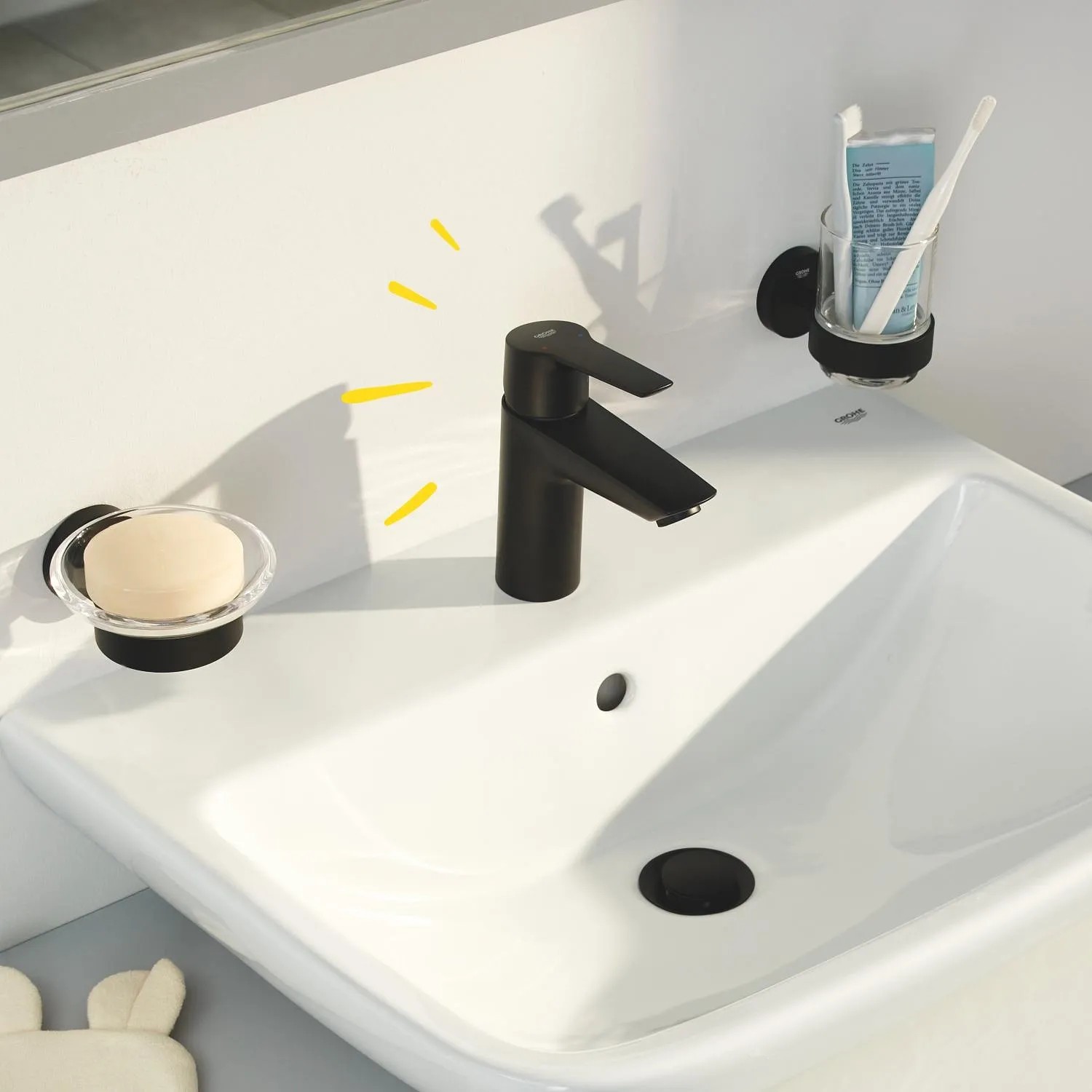 Schwarze Grohe QuickFix Waschtischarmatur Start S-Size auf weißem Waschbecken mit Seife und Zahnbürste.