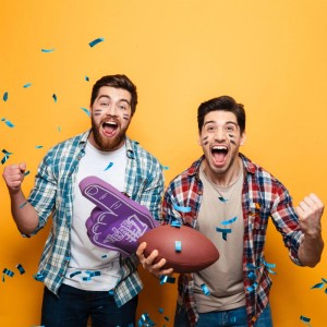 Zwei Männer jubeln im blauen Konfettiregen, einer mit Football. Perfekte Party-Stimmung für Konfettikanone.