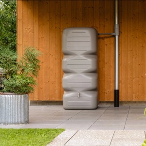 Garantia Gartentank Cubus 700 l in Betongrau vor Holzwand. Robuster Regenspeicher für Garten und Terrasse.