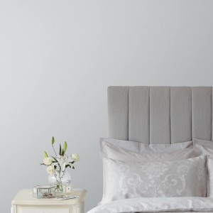 Laura Ashley Wandfarbe Slate White Hellgrau an Schlafzimmerwand mit Bett und Nachttisch.
