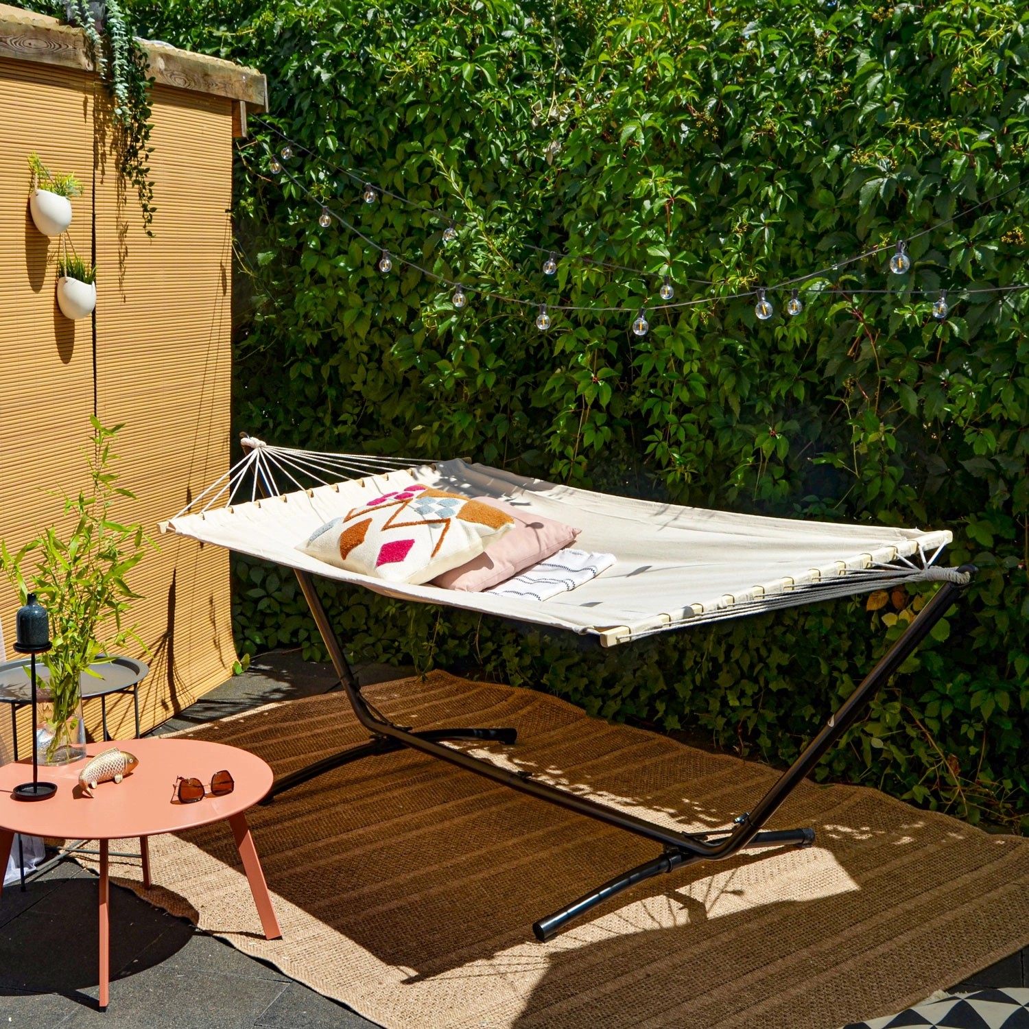 Beige AMANKA Hängematte 200x120 cm mit schwarzem Gestell (310 cm) im Garten.