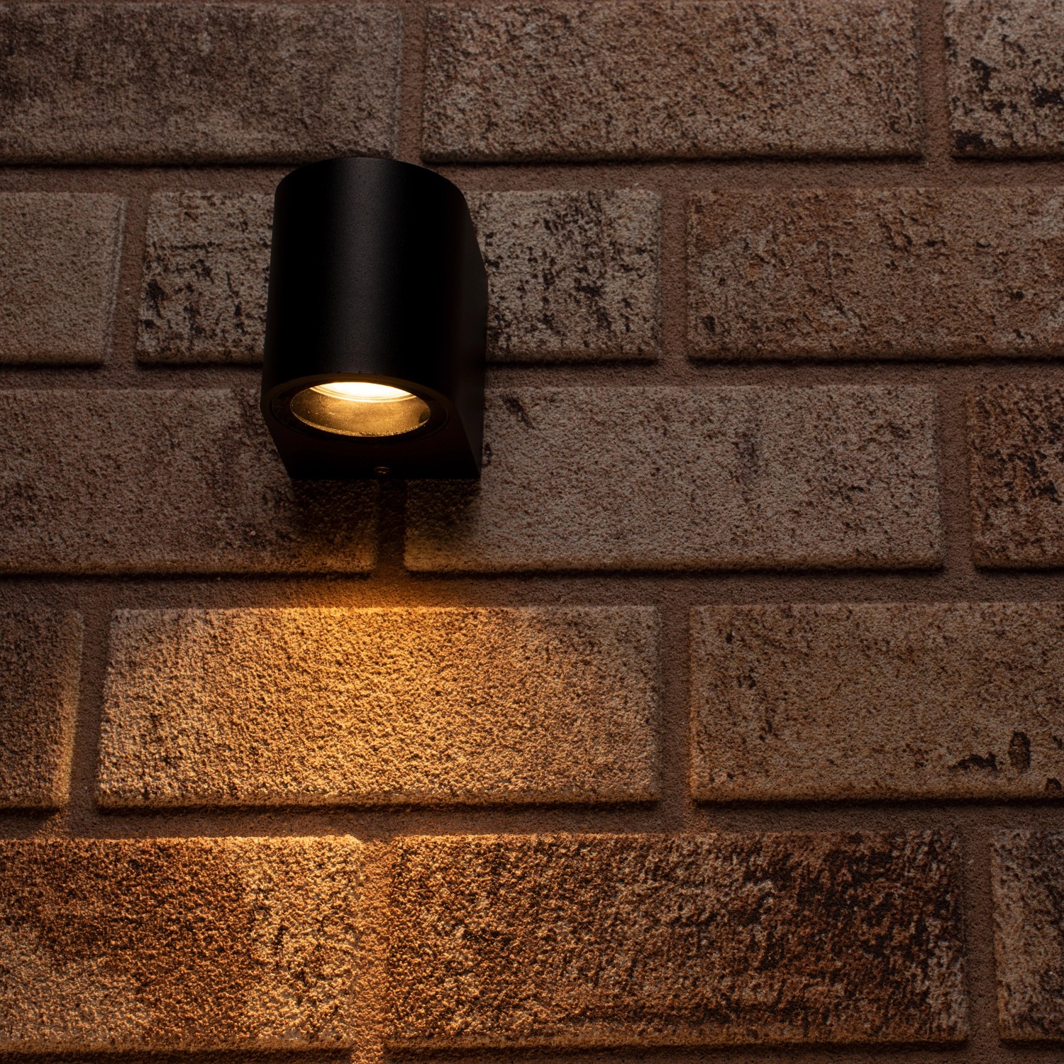 Schwarze, halbrunde LED`s light Außenwandleuchte an einer Backsteinwand.