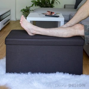 Dunkelbraune DuneDesign Faltbare Sitzbank/Truhe (76x38x38cm) als Garderobenbank mit Fuß auf der Sitzfläche.