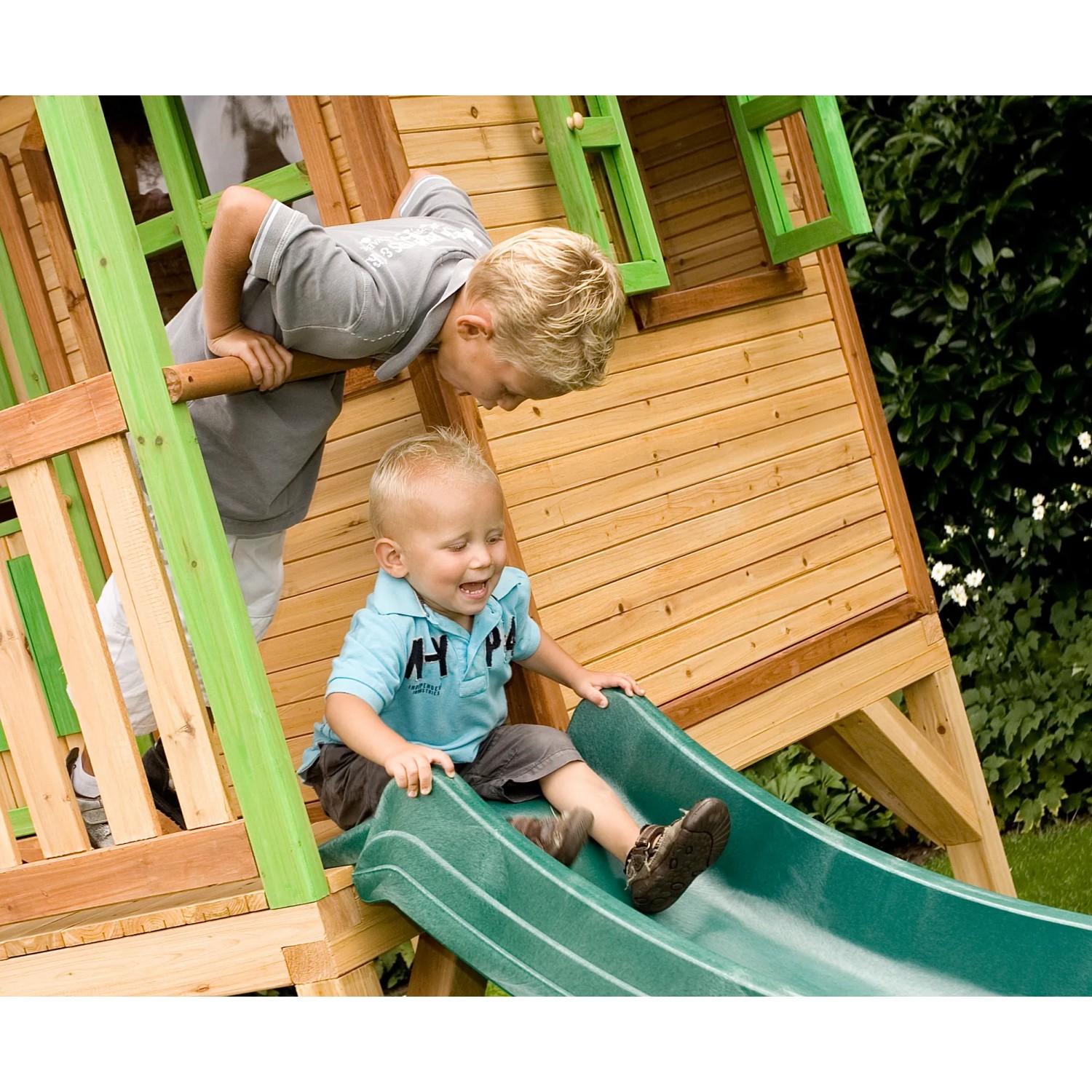 Axi Sarah Spielhaus mit grüner Rutsche: Kinder spielen im Garten.