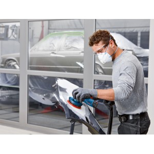 Mann schleift mit Bosch Akku-Exzenterschleifer GEX 12V-125 ein Karosserieteil. Schleifmaschine mit Staubabsaugung.