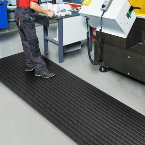 Schwarze KARAT Anti-Ermüdungsmatte Softer-Work-Mat 90x250cm mit Rippenstruktur am Arbeitsplatz.