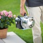 Mann trägt Gartenpumpe GP 3800E (900 W) mit Saugschlauch vor Garten. Edelstahlgehäuse.