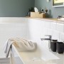 Schwarzer WENKO Zahnputzbecher Rotello mit Rillenstruktur und Bambus-Boden im Badezimmer.