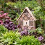 Holz Insektenhotel für Bienen und Nützlinge im Garten. Hausform mit Bambusröhren und Nistkammern.