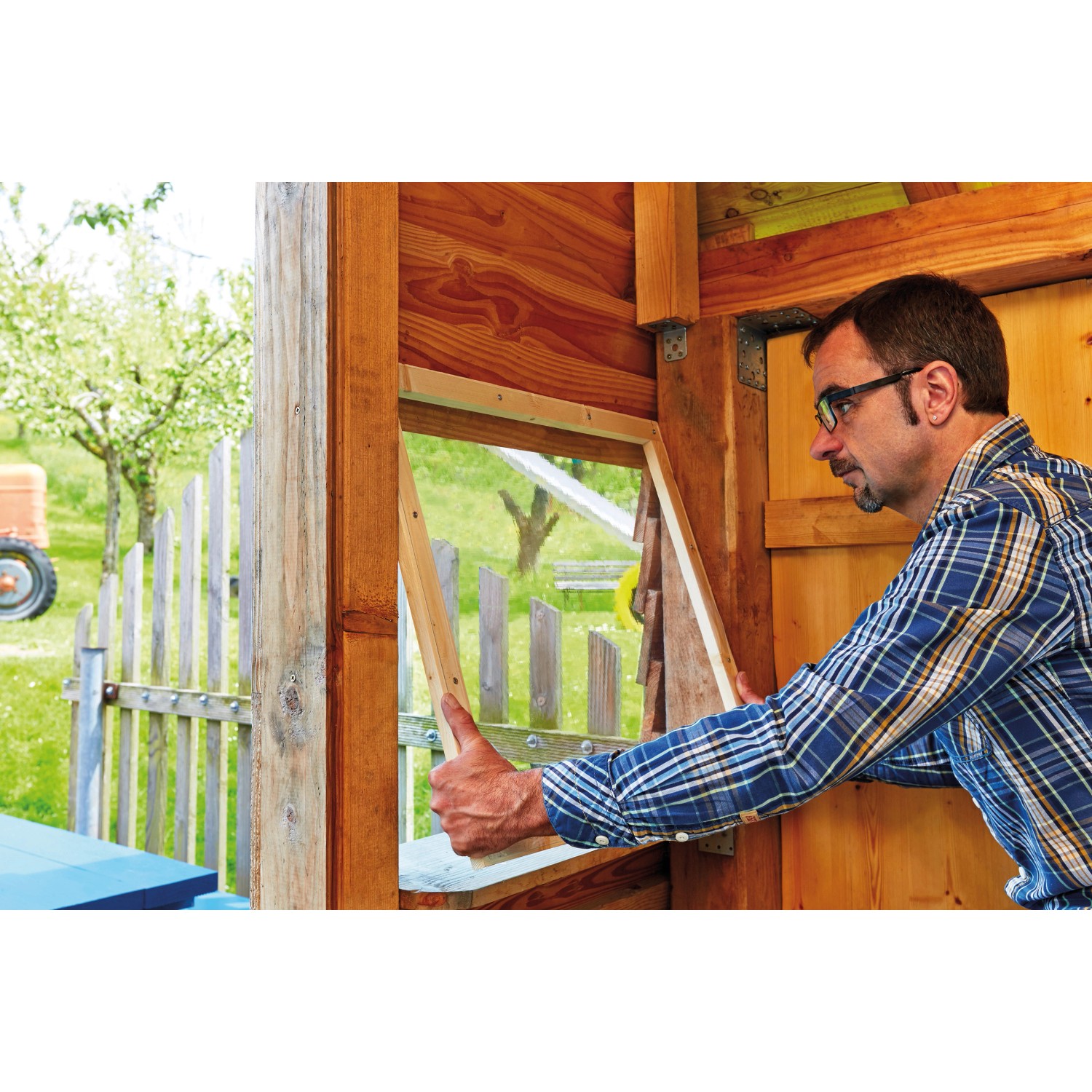 Mann montiert transparente Verglasungsfolie (125 cm) an einem Holzrahmen. Kunststoffbedachung für klare Sicht.