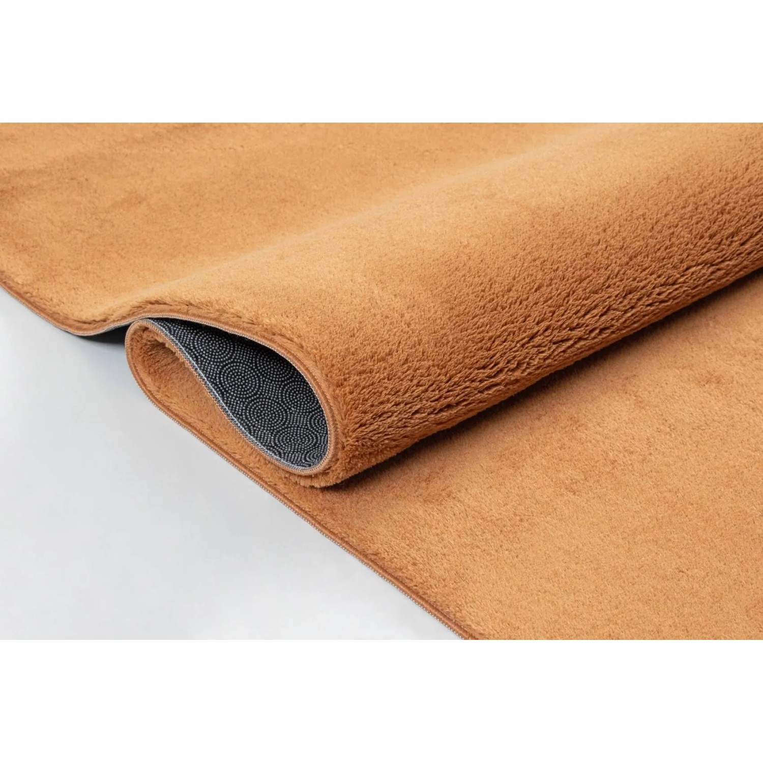 Orangefarbener Floornovo Hochflorteppich (340x240 cm), gerollt, mit rutschfester Unterseite.