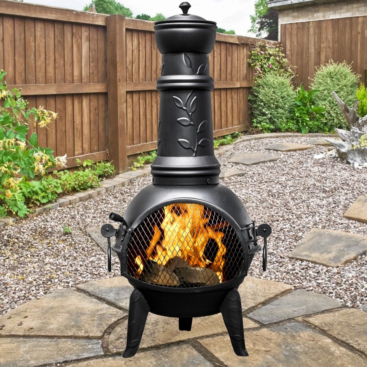 Buschbeck Mexiko-Ofen Leaf 136: Schwarze Feuerschale mit Grillfunktion und Blattmuster im Garten.