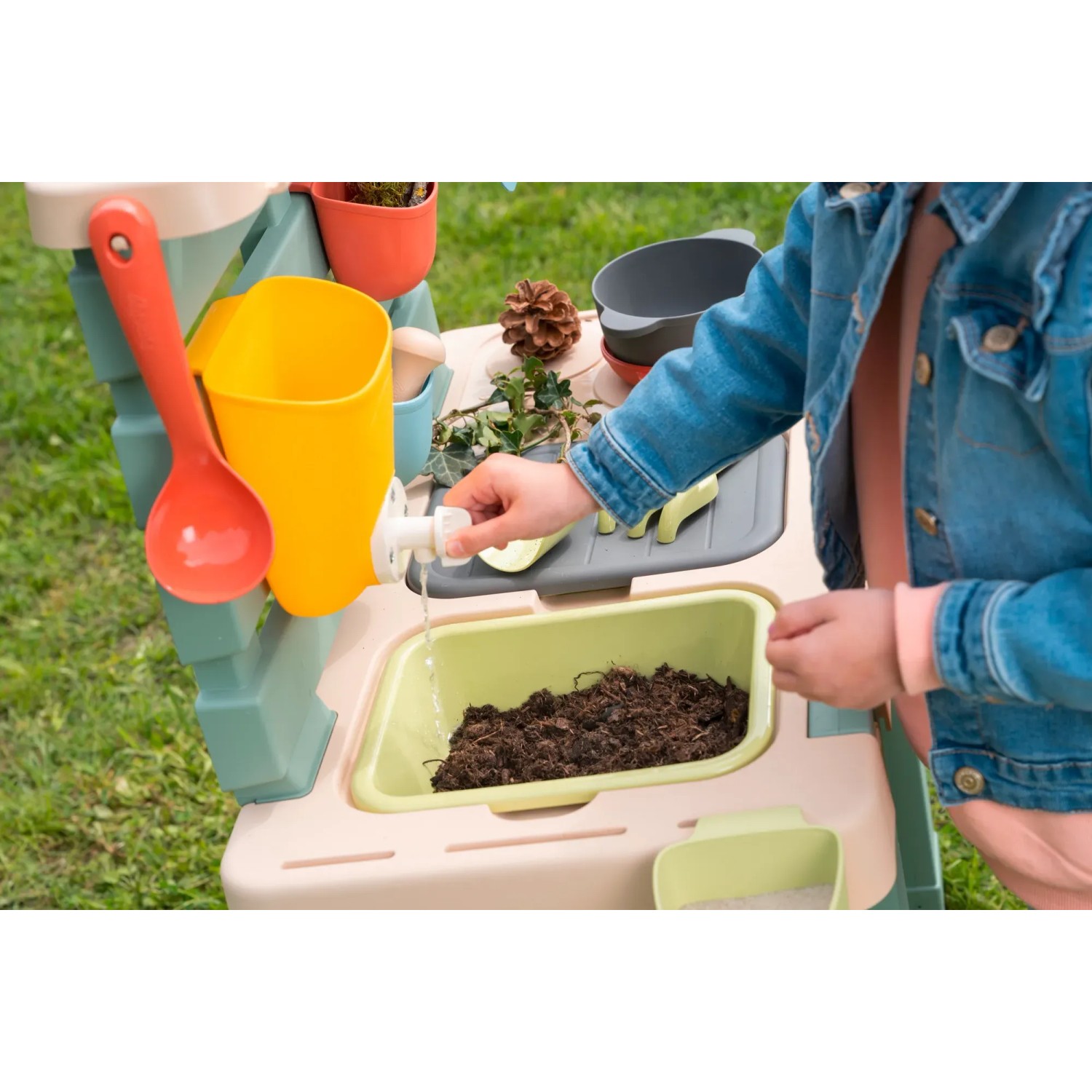 Bunte Smoby Matschküche Life mit Zubehör und Kind, das Wasser laufen lässt.