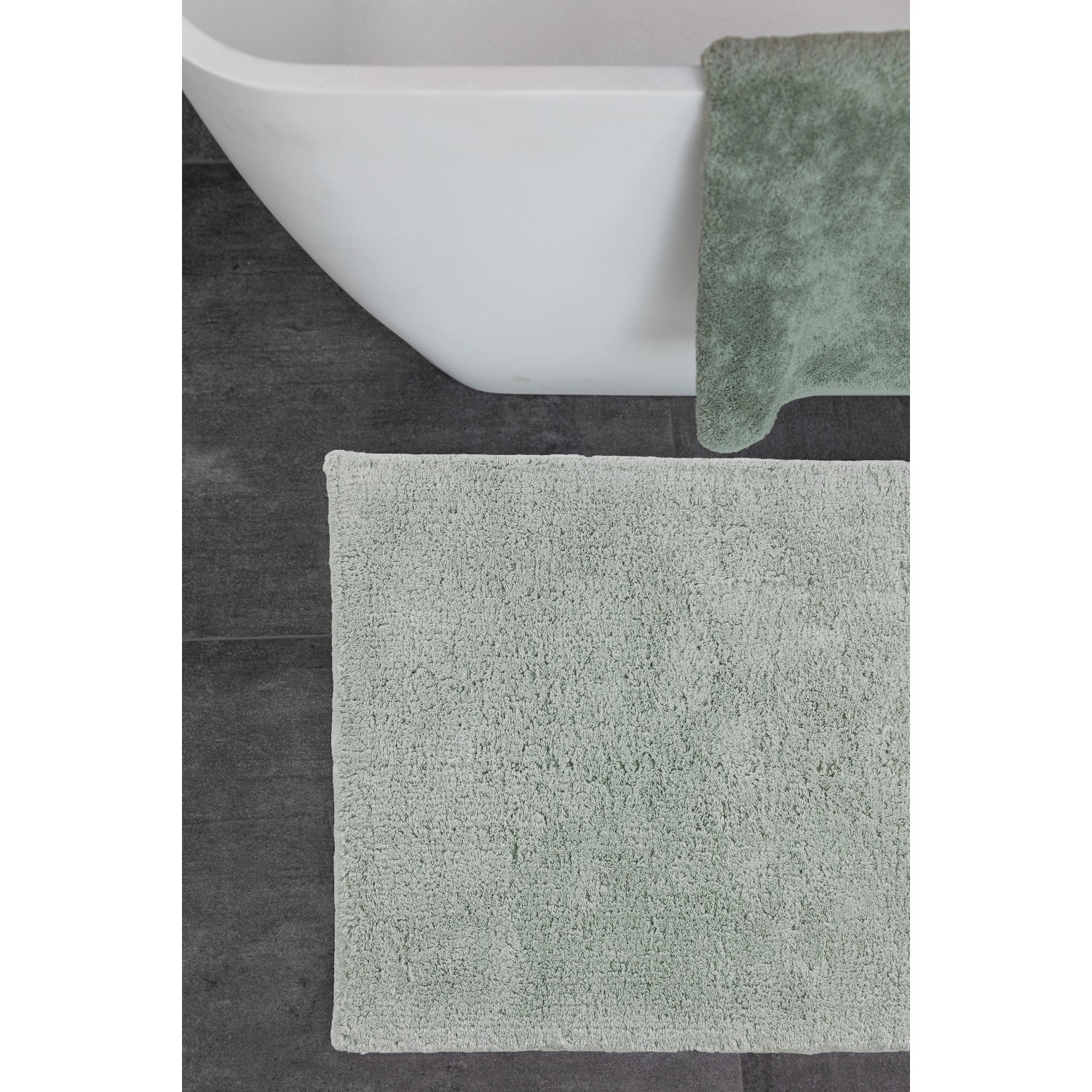 Schöner Wohnen Badmatte Bahamas, 40x60 cm, Uni Mint, vor Badewanne auf dunklem Untergrund.