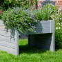 Graue Dobar Mährobotergarage mit Pflanzkasten, bepflanzt mit Blumen.