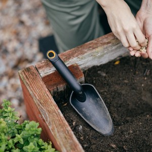 Fiskars Solid Blumenkelle (29 cm, Schwarz) im Einsatz beim Blumensetzen im Gartenbeet.