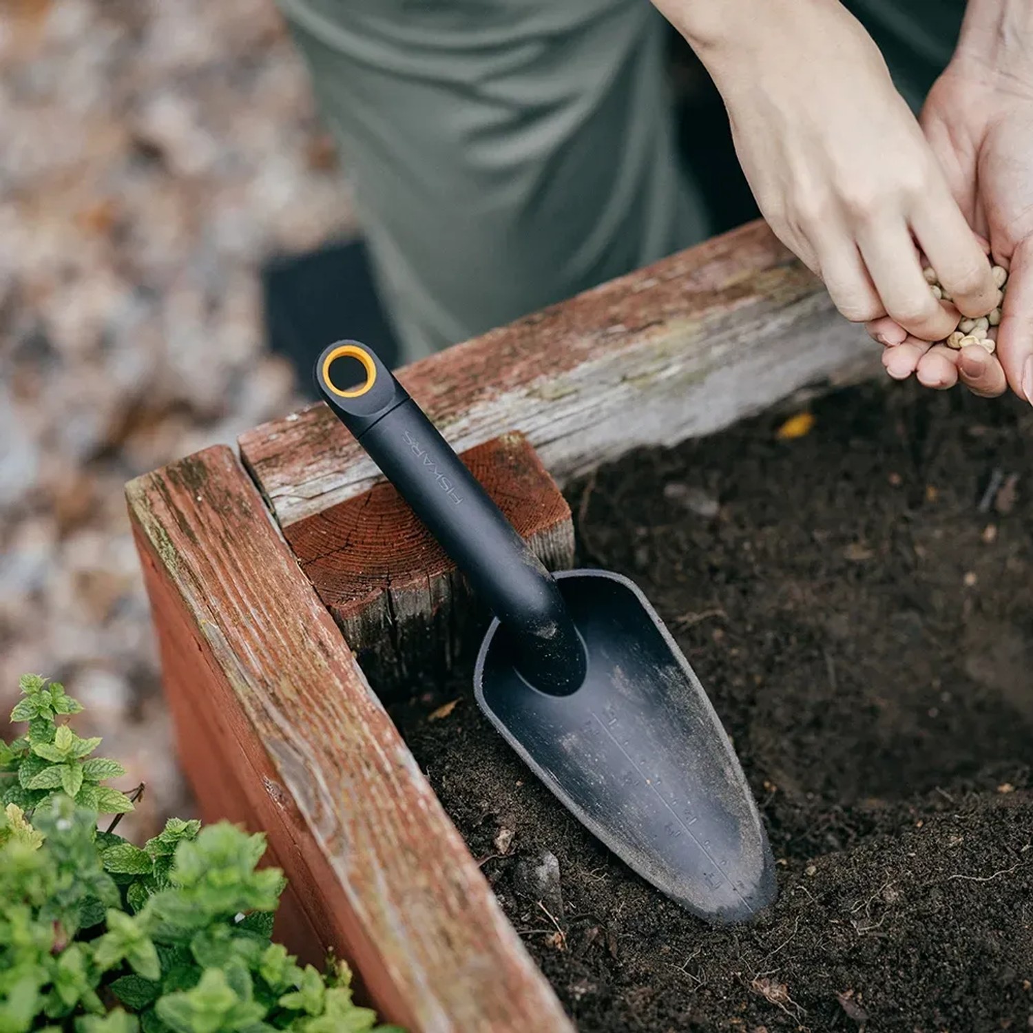 Fiskars Solid Blumenkelle (29 cm, Schwarz) im Einsatz beim Blumensetzen im Gartenbeet.