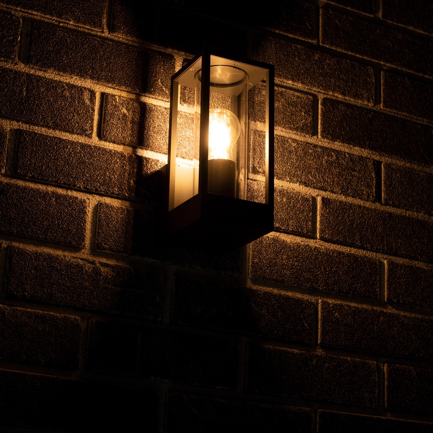 Eckige, anthrazitfarbene LED`s light Außenwandleuchte mit Glas auf Backsteinmauer.