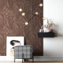 Newroom Savina Bronze Vliestapete mit strukturierten Palmenblättern in warmen Brauntönen an einer Wand. Dekorative Tapete.