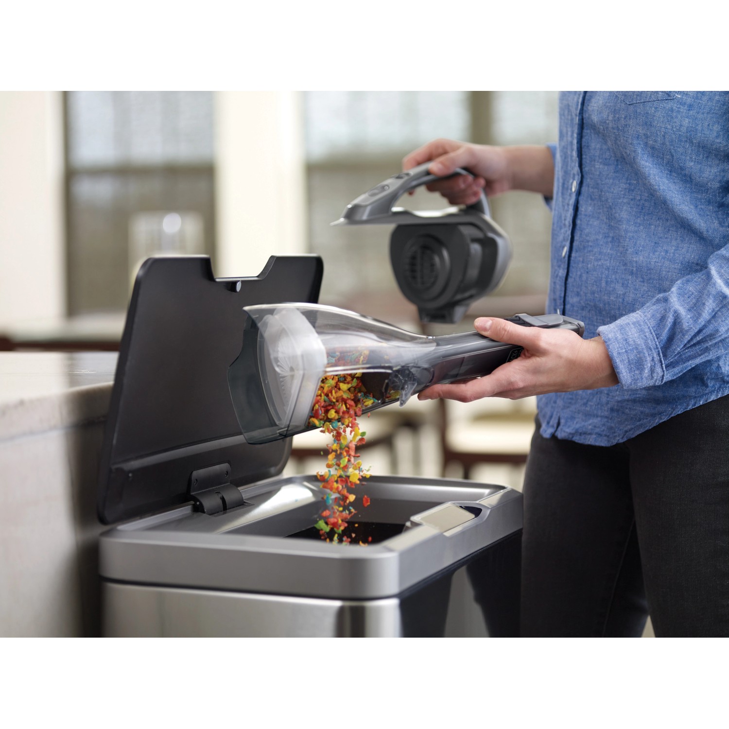 Black+Decker Akku-Handstaubsauger DVA320J beim Entleeren über einem Mülleimer.