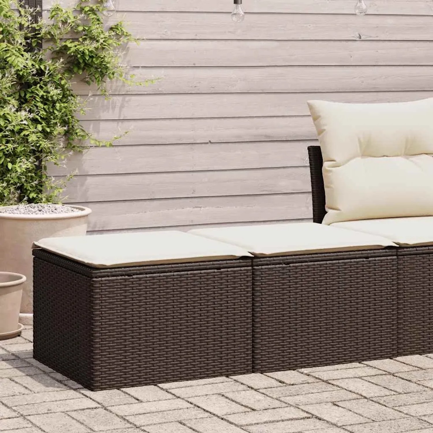 Braune 2-teilige Garten-Sofagarnitur aus Rattan mit cremefarbenen Kissen.