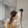 Frau unter der Dusche mit Schütte Handbrause Capri, schwarz matt. 3-fach verstellbare Duschbrause.