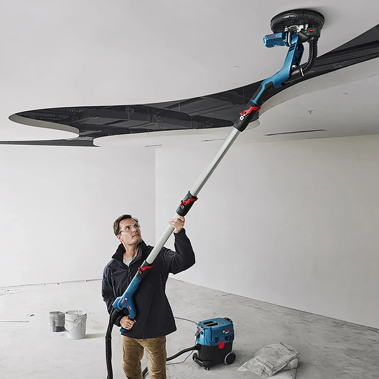 Bosch Professional GTR 55-225 Trockenbauschleifer im Einsatz an einer Decke, mit Staubsauger.