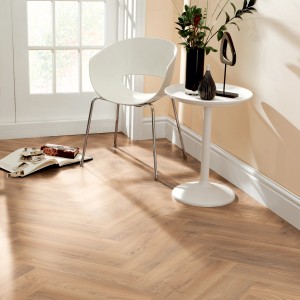 Verlegtes Kronoflooring Herringbone Laminat Historic Oak im Wohnraum mit Stuhl und Tisch.
