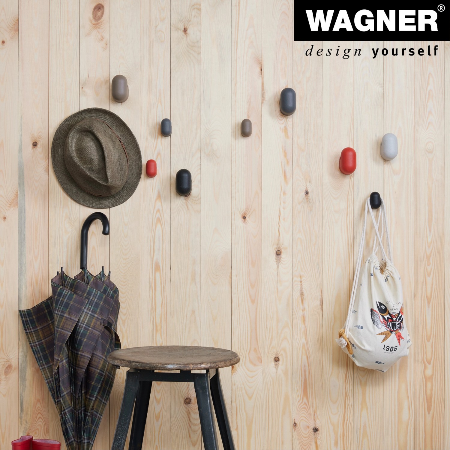 Wand mit Wagner Wandhaken Pill Set in verschiedenen Farben, genutzt für Hut, Regenschirm und Tasche.