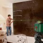 Bosch UniversalLevel 360 Kreuzlinienlaser im Einsatz im Badezimmer mit grünen Laserlinien.
