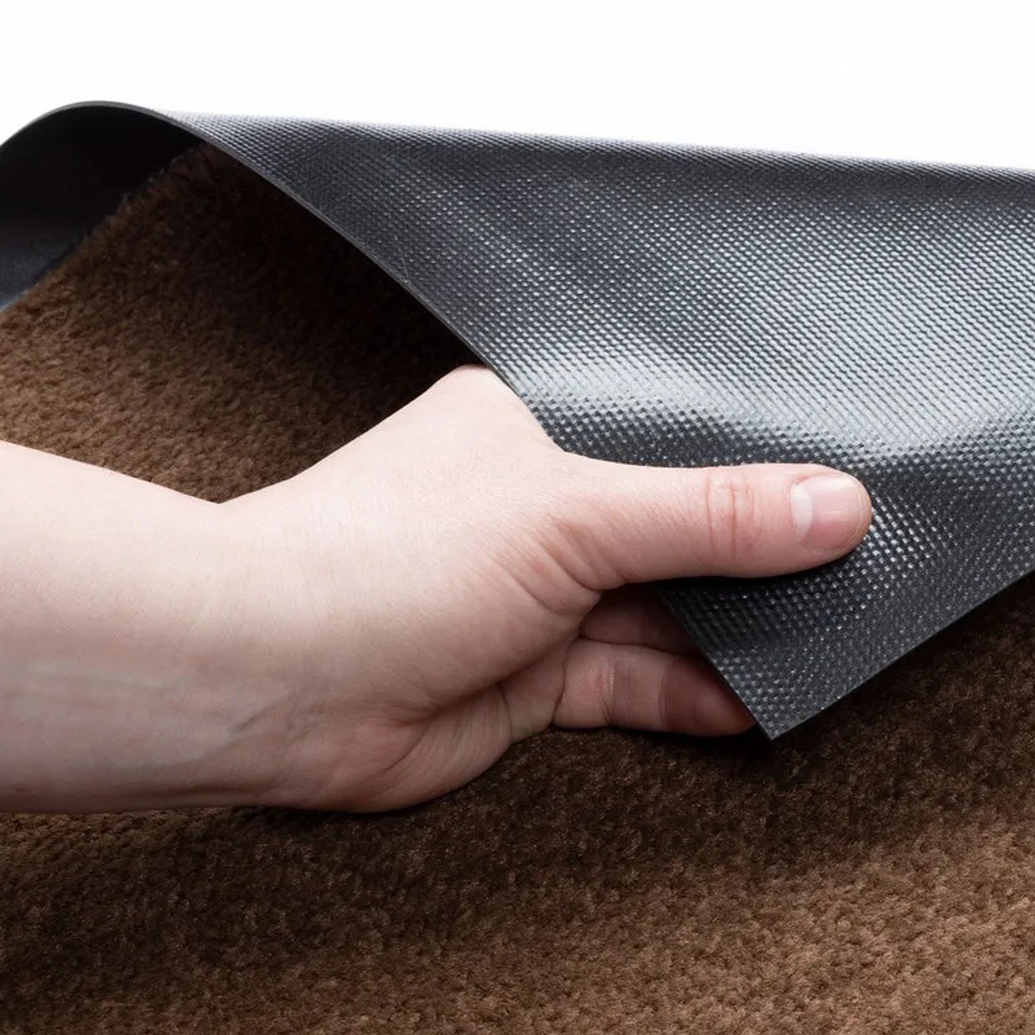 Braune KARAT Fußmatte Performa mit rutschfester Rückseite wird von einer Hand angehoben.